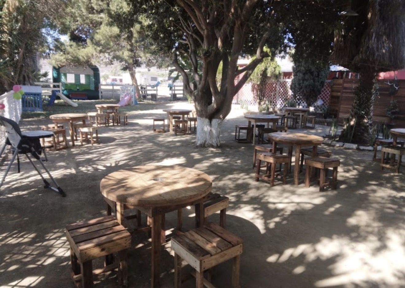 Mesas redondas de madera y bancos rústicos en el jardín